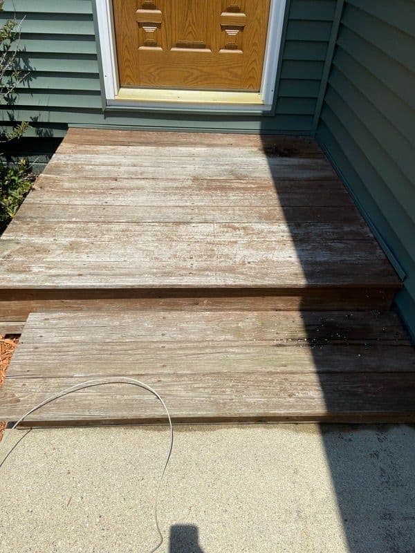 Weathered wooden steps leading to a front door on a green house exterior.